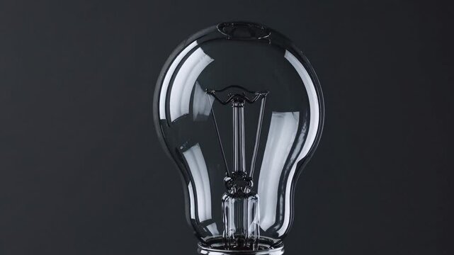 Illuminating Idea: A close-up captures a clear lightbulb, its glass form reflecting the potential of an ingenious idea, with a sleek, dark background.