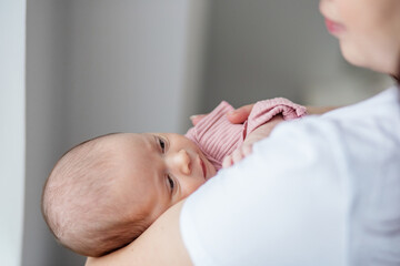 Mother cradles newborn baby in cozy indoor setting during a quiet afternoon. Copy space
