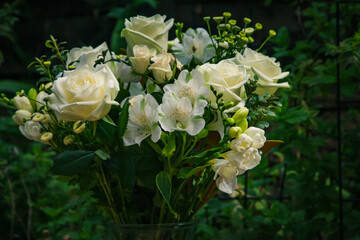 A lush bouquet of fresh white roses and delicate blooms arranged in a glass vase, set against a vibrant green garden backdrop. Perfect for weddings, sympathy, or elegant home decor inspiration