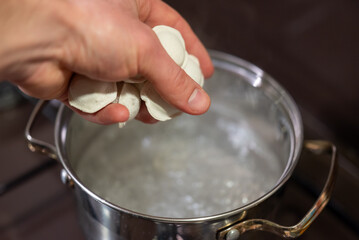 Boiling dumplings in a pot creates a delicious and comforting meal. A hand drops dumplings into boiling water, creating steam and anticipation for a flavorful dish