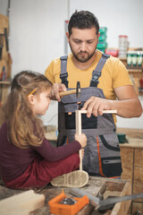 Father and daughther making wooden frame in workshop