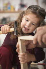 Father and daughther making wooden frame in workshop