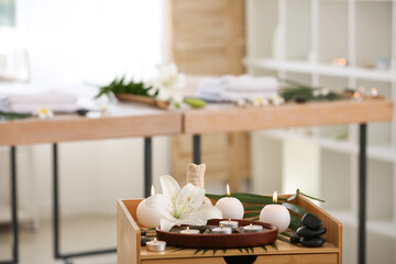 Spa composition with burning candles and lily flower on table in salon, closeup