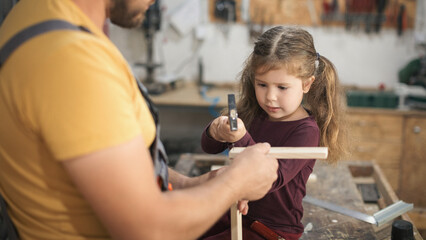 Father and daughther making wooden frame in workshop