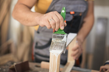 Father and daughther painting wooden frame in workshop