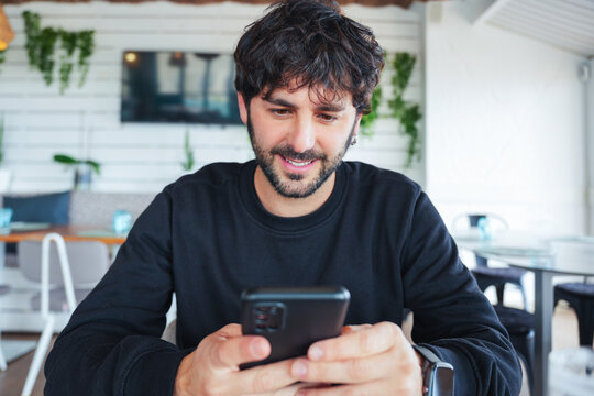 Happy customer using mobile phone app in cafe, enjoying online experience
