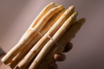 High-quality image of a hand holding a bunch of fresh, white asparagus. Perfect for food blogs,...