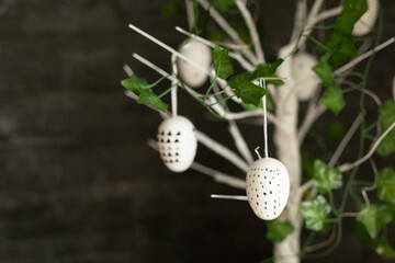 White eggs with geometric patterns hang from a faux tree branch, perfect for spring decor.