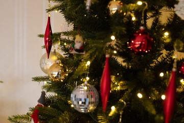 Close-up of a decorated Christmas tree with red and gold ornaments, fairy lights, and festive...