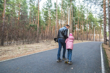 Fototapeta premium Father and daughter riding skateboards in the forest.