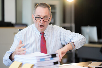 Stressed caucasian maturebusinessman working in the office.