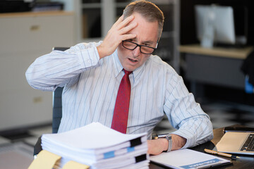 Stressed caucasian maturebusinessman working in the office.