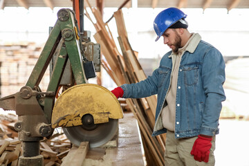 Male carpenter using sawing machine at sawmill