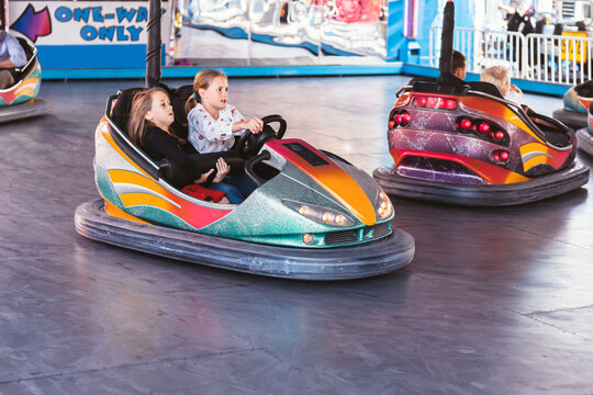 younger sister holding on tight as older sister drives a dodgem car