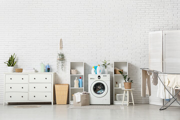 Interior of light laundry room with washing machine, shelving units and dryer