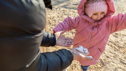 Grandfather playing with his granddaughter on the playground in the park in winter