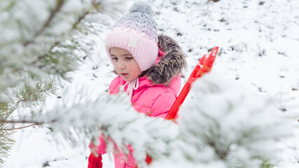Little girl playing in a snowy park in winter