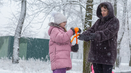 Grandmother with grandchildren in warm clothes playing outdoors in winter park, enjoying snowy...