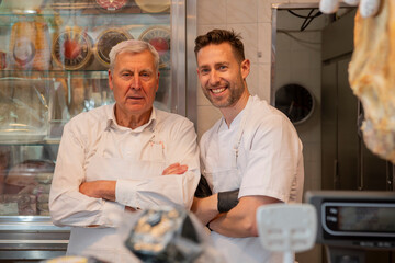 Butchers smiling in butcher shop with meat display case