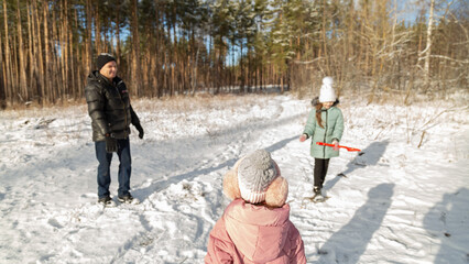 Playful family enjoying snowball fight in snowy winter park