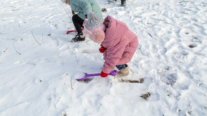 Little girls play with snow with her grandfather in winter forest