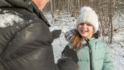 Little girls with her grandfather walk in a snowy forest, have fun together