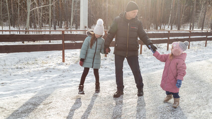 Little girls with her grandfather walking in park on snowy winter day