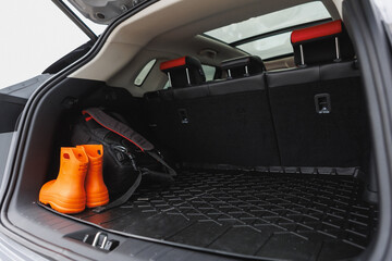 A pair of bright orange rain boots are sitting in the trunk space of a car