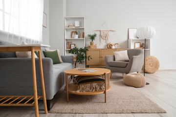 Interior of light living room with grey sofa, armchair and lamp