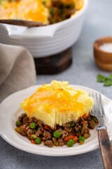 Homemade shepherd’s pie with mashed potatoes and minced meat, served in a cozy rustic kitchen setting. Comforting classic British dish perfect for cozy meals and homestyle food photography.