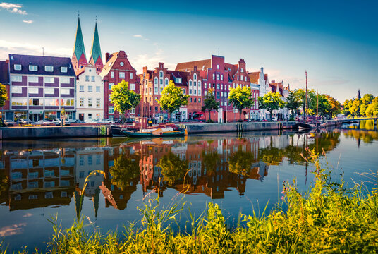 Exciting summer cityscape of Lubeck town, distinguished by Brick Gothic architecture, Germany, Europe. Beautiful morning scene of Trave Canal with white yachts. Traveling concept background.