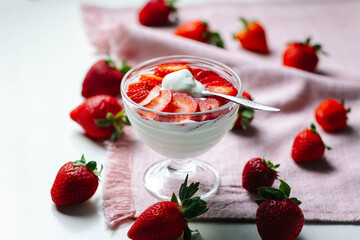 Spoonful of Greek yogurt and strawberries being lifted by a hand, symbolizing fresh and delicious dairy-based nutrition.