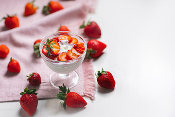 Fresh sliced strawberries over rich Greek yogurt, with a hand about to enjoy a spoonful. Clean, minimalist food photography.