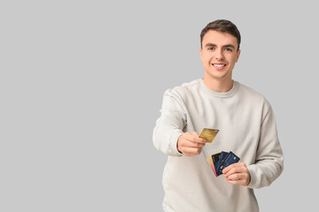 Young man with credit cards on light background