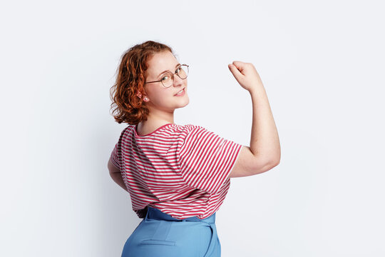 A beautiful, successfu and young woman showing off her strong muscles. Authentic gbusiness woman showing strength.