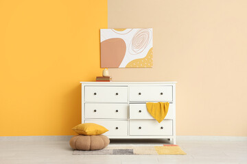 Interior of stylish room with white commode, pouf and painting