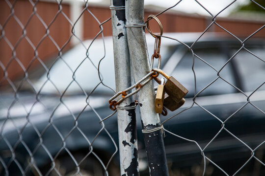 Out of focus car behind chained and padlocked fence gates