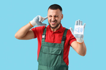 Male worker with speaker icon suffering from loud noise on blue background