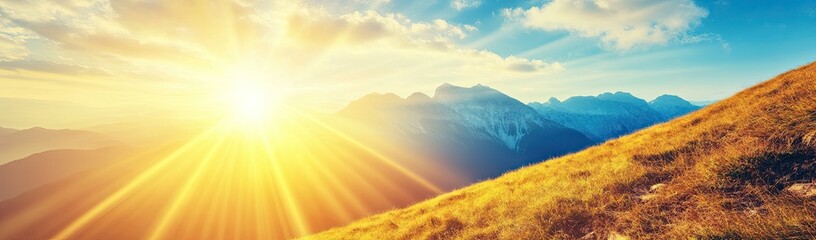 Golden sunset over mountain peaks.  Sunlight rays stream down a hillside covered in tall grass