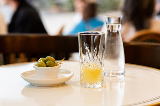 Un pastis et des olives vertes servis sur une table en terrasse, ap&eacute;ritif dans le sud de la France