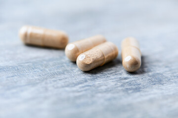 Reishi capsules. Concept for a healthy dietary supplementation. Wooden background. Soft focus. Close up.	
