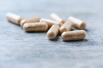 Reishi capsules. Concept for a healthy dietary supplementation. Wooden background. Soft focus. Close up.	