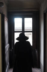 Silhouette of Woman with Hat Looking Out the Window Indoors