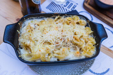 Creamy Mac and Cheese with Parmesan in Cast Iron Skillet Served at Restaurant Table