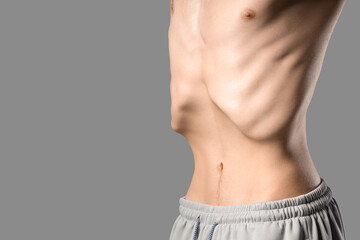 Naklejka premium Young man with anorexia on grey background, closeup