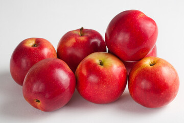 A close-up view of a pile of shiny red apples arranged on a clean white background, highlighting their fresh texture and vibrant color. Perfect for food advertising, health, and organic produce themes