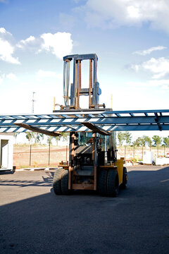 Large forklift carrying metal framework on a work site