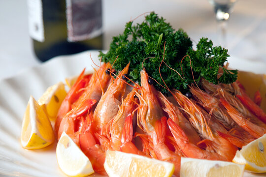 Fresh prawns arranged on a plate with lemon slices