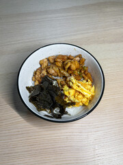 Rice bowl topped with chicken, egg, and seaweed.