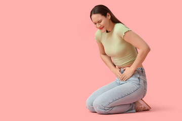 Suffering young woman on pink background. Cystitis concept